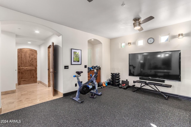 workout room with arched walkways, baseboards, and a ceiling fan