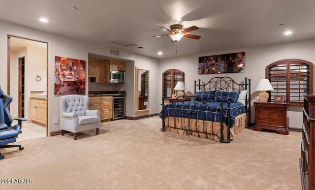 bedroom with ceiling fan, beverage cooler, ensuite bath, and light carpet