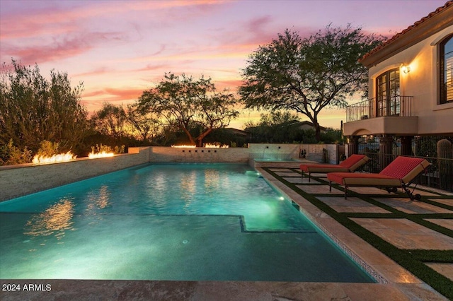 pool at dusk with a patio area and a fenced in pool