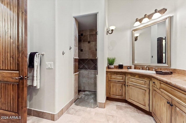 full bathroom featuring a tile shower, vanity, and baseboards
