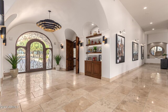 interior space featuring baseboards, recessed lighting, arched walkways, and a high ceiling