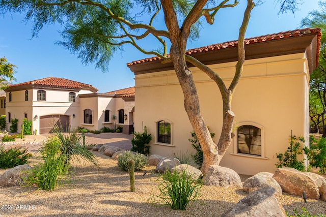 mediterranean / spanish home with a tiled roof, driveway, and stucco siding
