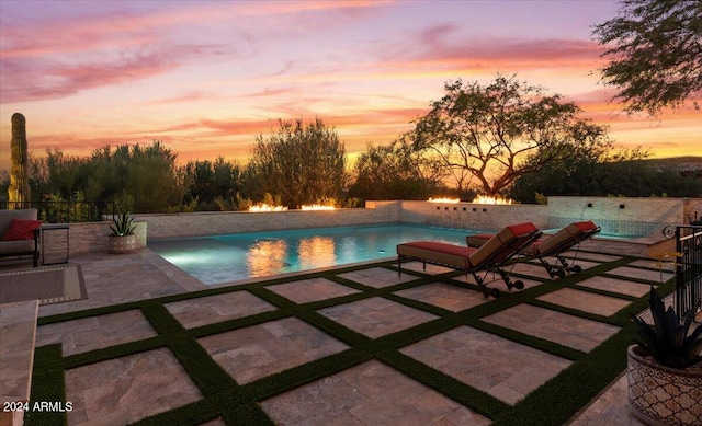 pool at dusk featuring a patio area