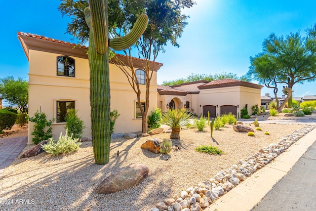 mediterranean / spanish-style home with a garage, stucco siding, driveway, and a tile roof