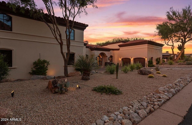 view of front of home featuring driveway, stucco siding, a tiled roof, and an attached garage