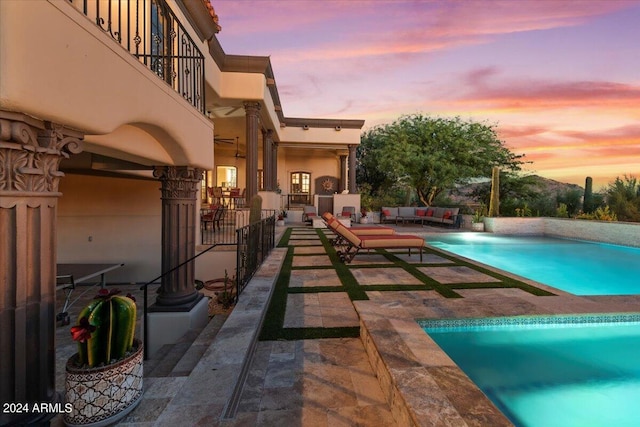 pool at dusk with an outdoor living space and a patio area