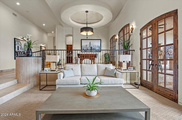 living room featuring light colored carpet, a raised ceiling, french doors, and plenty of natural light