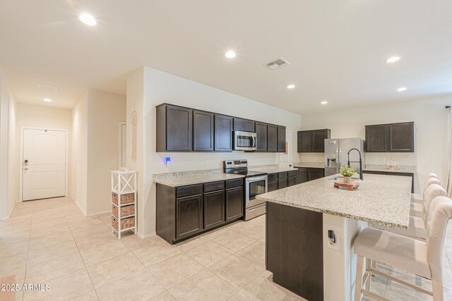 36467 W Pampoloma Ave, Maricopa, AZ 85138 - kitchen featuring appliances with stainless steel finishes, a sink, recessed lighting, a breakfast bar area, and light stone counters