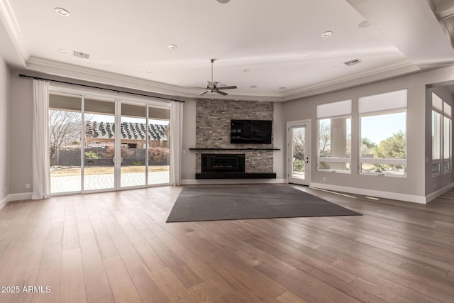 unfurnished living room featuring ornamental molding, wood-type flooring, a wealth of natural light, and a fireplace