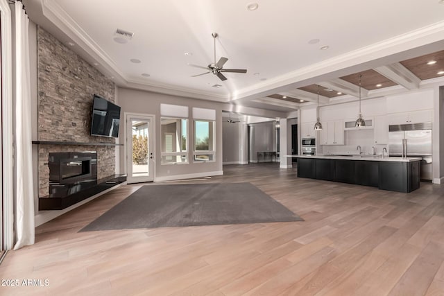 unfurnished living room with ceiling fan, ornamental molding, a fireplace, and light wood-type flooring