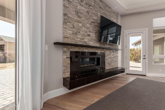 living room featuring a tiled fireplace, hardwood / wood-style flooring, and crown molding