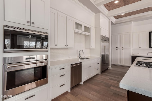 kitchen with sink, white cabinetry, built in appliances, beamed ceiling, and light stone countertops