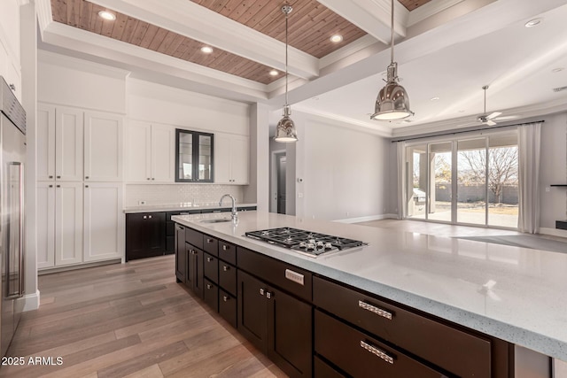 kitchen with appliances with stainless steel finishes, white cabinetry, decorative backsplash, hanging light fixtures, and beam ceiling