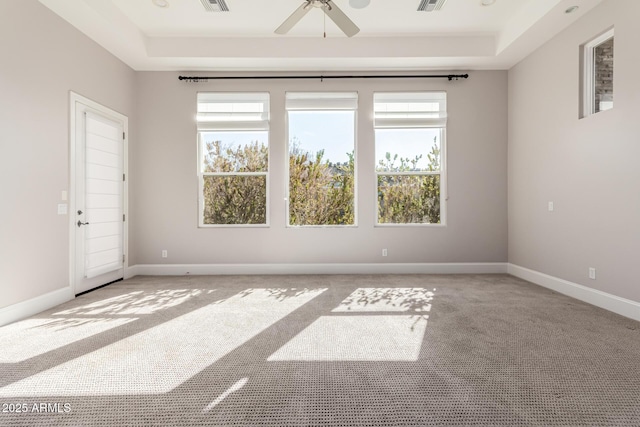 carpeted empty room with ceiling fan and a raised ceiling