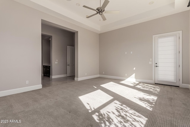 carpeted empty room with ceiling fan and a tray ceiling