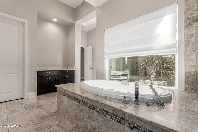 bathroom featuring a relaxing tiled tub and vanity