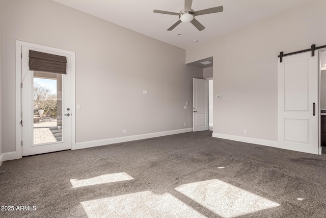 unfurnished room with a barn door, carpet flooring, and ceiling fan