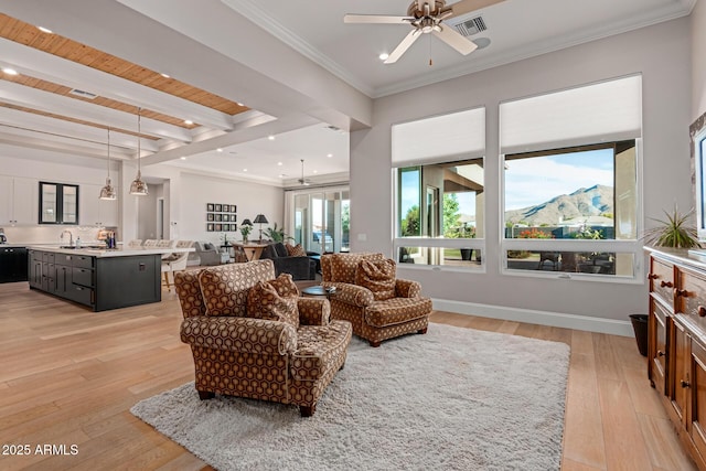 living room with ornamental molding, ceiling fan, a mountain view, beam ceiling, and light hardwood / wood-style flooring