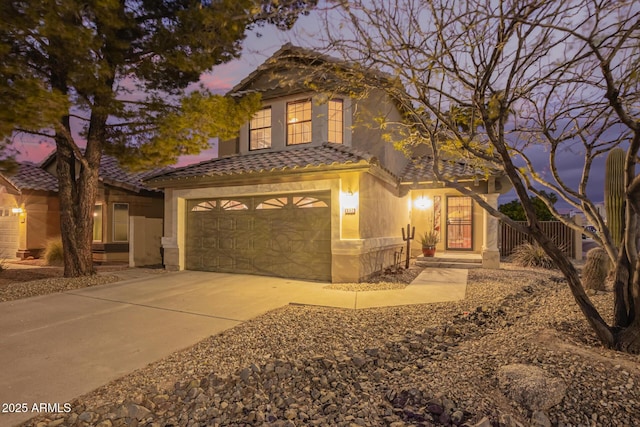 traditional home featuring a tiled roof, stucco siding, driveway, and an attached garage