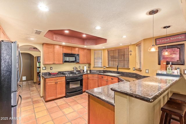 kitchen featuring visible vents, a tray ceiling, a peninsula, arched walkways, and black appliances