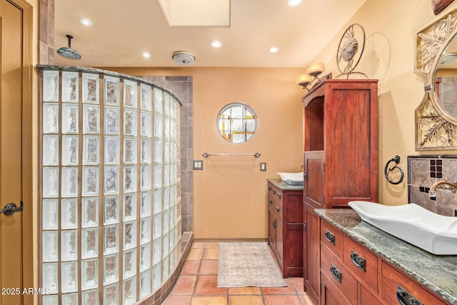 bathroom featuring tile patterned flooring, two vanities, recessed lighting, tiled shower, and a sink