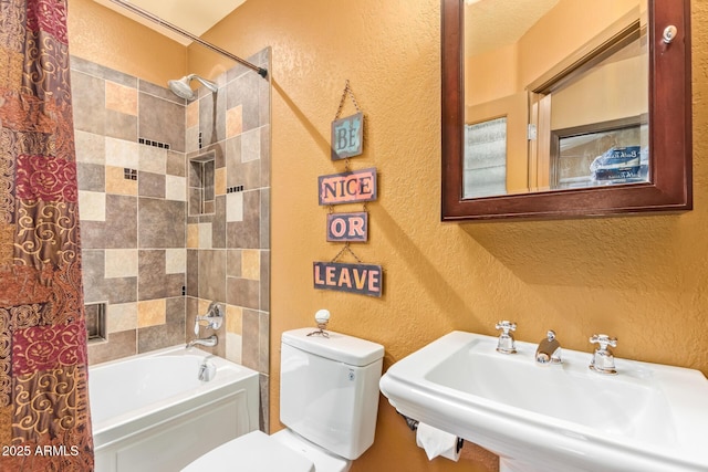 full bath featuring a sink, toilet, shower / bath combination, and a textured wall