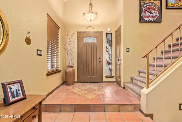 entrance foyer with tile patterned floors, stairway, and baseboards