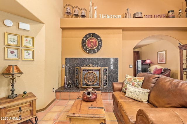 living area featuring tile patterned floors, baseboards, arched walkways, and a high end fireplace