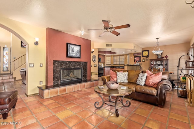 living room featuring visible vents, arched walkways, a textured ceiling, and a fireplace