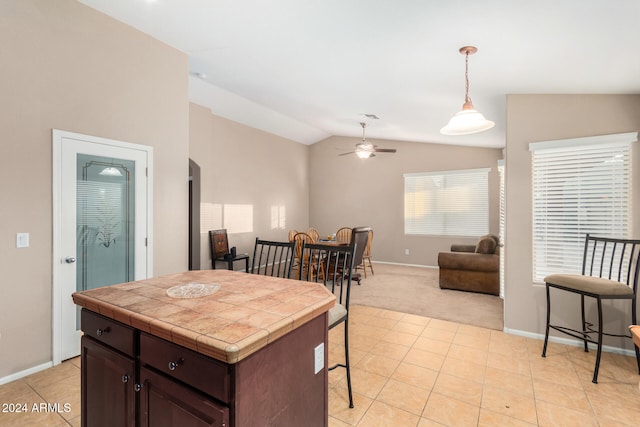 kitchen featuring pendant lighting, vaulted ceiling, ceiling fan, dark brown cabinets, and a kitchen island