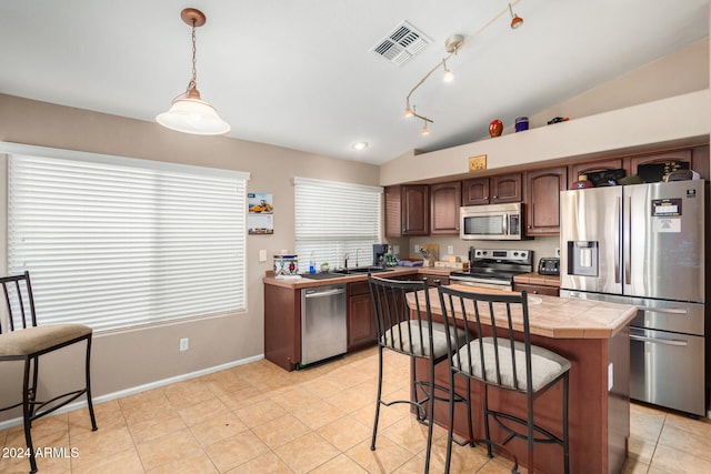 kitchen with a center island, lofted ceiling, appliances with stainless steel finishes, decorative light fixtures, and dark brown cabinetry