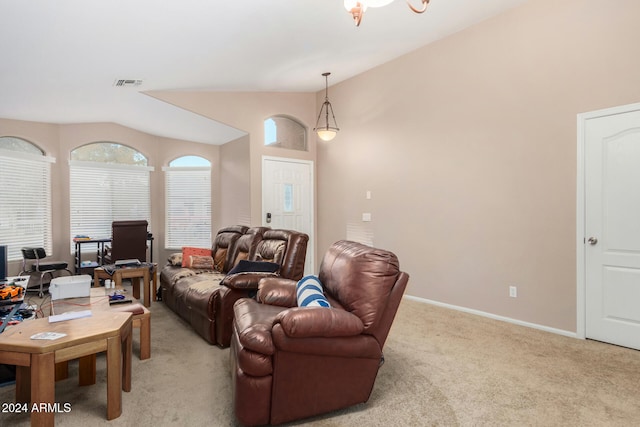 carpeted living room with a notable chandelier and vaulted ceiling