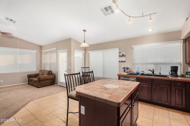 kitchen featuring tile countertops, lofted ceiling, light carpet, sink, and a kitchen island