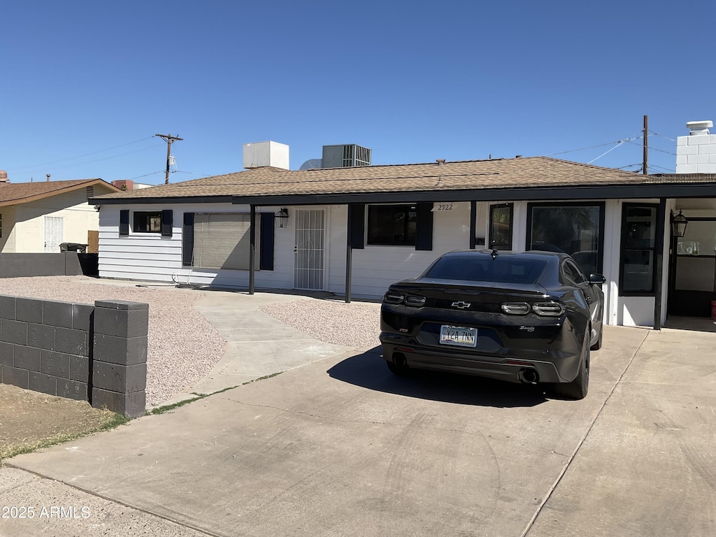 ranch-style home with fence, central AC unit, a chimney, and a shingled roof