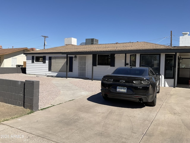 ranch-style home with fence, central AC unit, a chimney, and a shingled roof