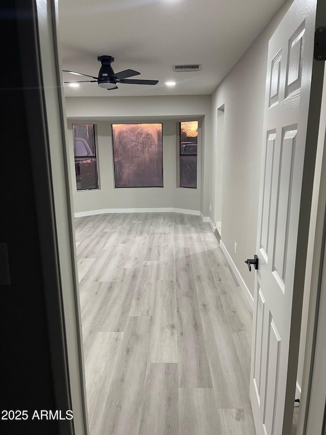 corridor with visible vents, light wood-type flooring, and baseboards