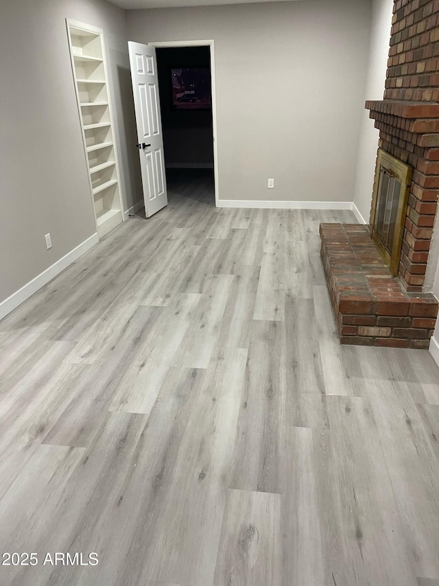 unfurnished living room with baseboards, wood finished floors, and a fireplace