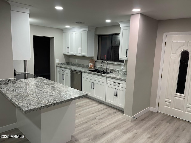 kitchen with white cabinets, light wood-type flooring, and a sink