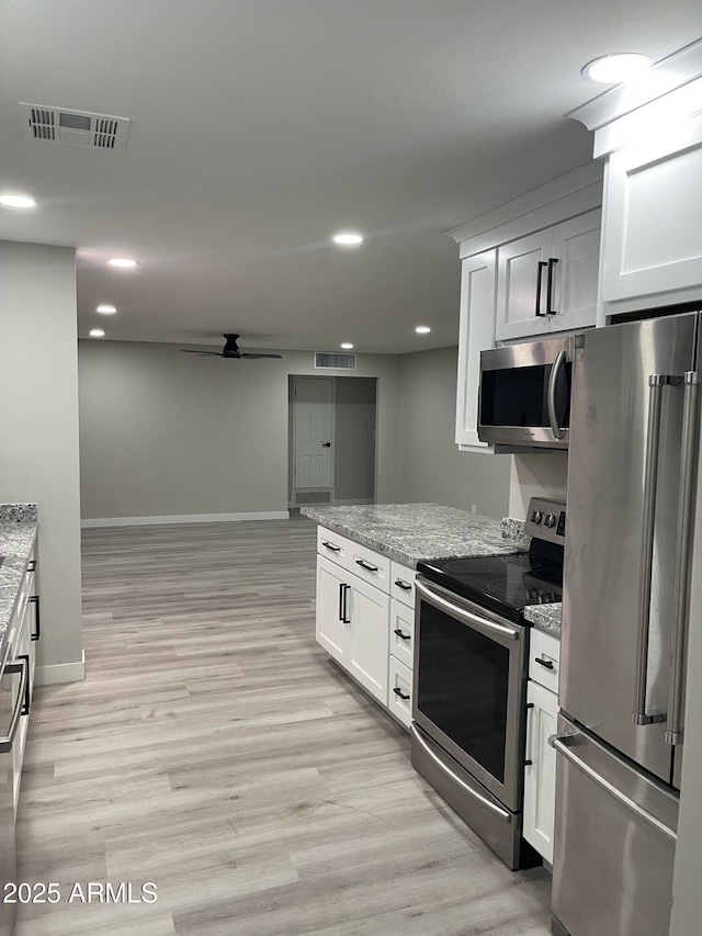 kitchen with visible vents, light wood-type flooring, light stone counters, stainless steel appliances, and white cabinetry