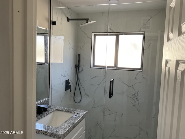 bathroom with a marble finish shower and vanity