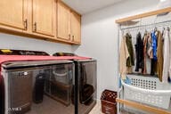 clothes washing area featuring cabinets and washing machine and clothes dryer