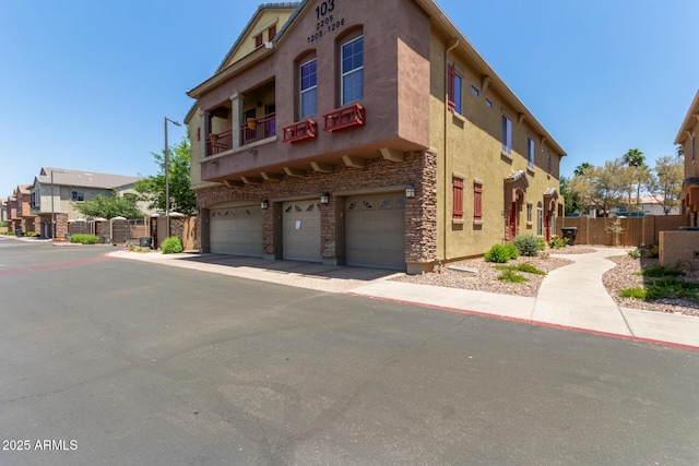 1350 S Greenfield Rd Unit 2205, Mesa, AZ 85206 - view of front of home with a garage, fence, stone siding, stucco siding, and a balcony