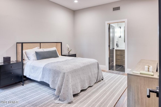 bedroom with ensuite bath and light hardwood / wood-style flooring