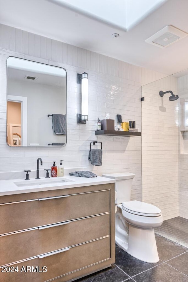 bathroom featuring backsplash, a tile shower, vanity, tile patterned flooring, and toilet