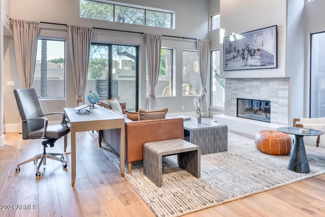 home office featuring a healthy amount of sunlight, a fireplace, and light hardwood / wood-style flooring