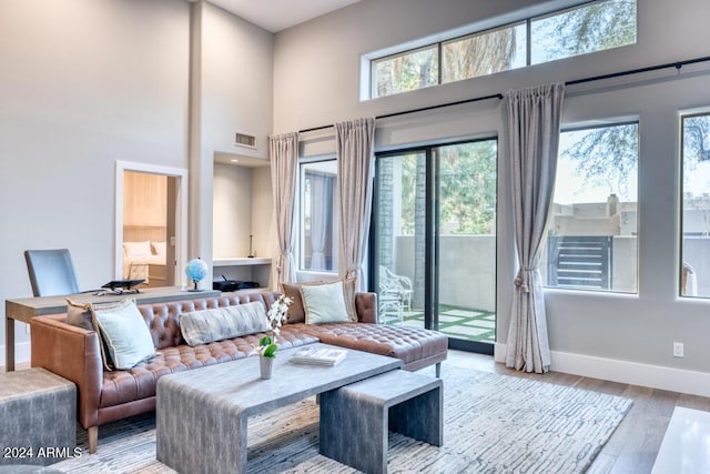 living room with a towering ceiling, light hardwood / wood-style floors, and plenty of natural light