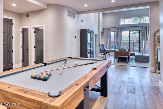 game room with a high ceiling, pool table, and light hardwood / wood-style flooring