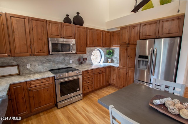 5120 N Juniper Loop, Pine, AZ 85544 - kitchen with backsplash, stainless steel appliances, light wood-style flooring, and brown cabinetry