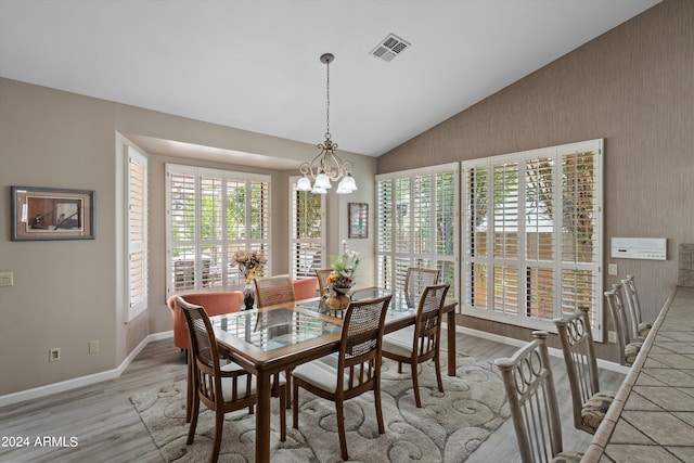 dining space with light hardwood / wood-style flooring, a notable chandelier, and vaulted ceiling