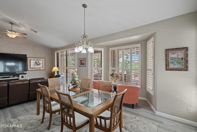 dining space featuring a wealth of natural light, vaulted ceiling, ceiling fan with notable chandelier, and light hardwood / wood-style floors